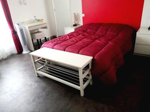 1 dormitorio con cama roja y mesa blanca en chambre avec salle de bain privatisée avec petit déjeuner compris, en Auxonne