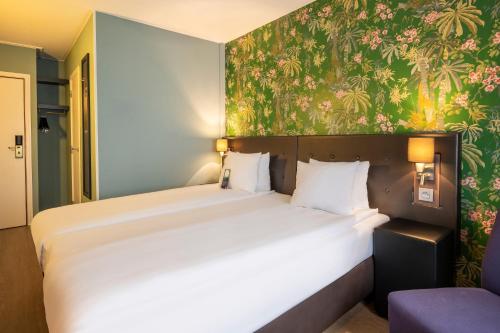 a bedroom with a large bed with a floral wallpaper at Thon Hotel Brussels Airport in Diegem