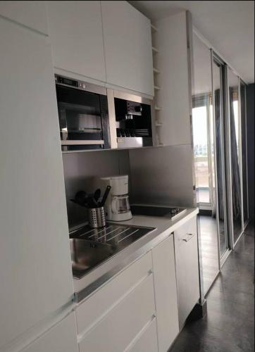 une cuisine avec des armoires blanches et un évier dans l'établissement Village Naturiste Cap d'Agde Le Vip, au Cap d'Agde