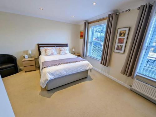a bedroom with a bed and a chair and windows at SoHot Stays-Garden Apt-Free Parking Ground Flr in Kent