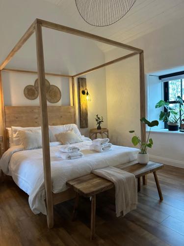 - une chambre avec un lit à baldaquin en bois et une table dans l'établissement Croft Cottage by Mourne Homestays, à Glasdrumman