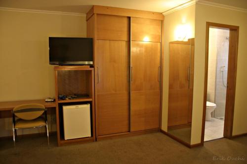 a room with a large wooden cabinet with a television at Barbur Plaza Hotel in Ponta Grossa