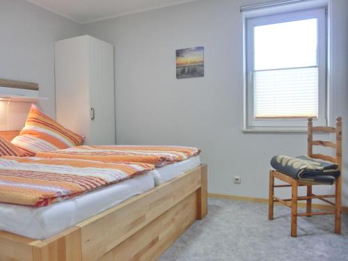 ein Schlafzimmer mit einem Bett, einem Stuhl und einem Fenster in der Unterkunft Ferienhaus FH9 in Graal-Müritz