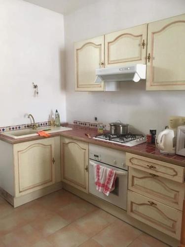 une cuisine avec des armoires blanches et un four à plaques de cuisson dans l'établissement Maison de village en montagne, à Saint-Lary