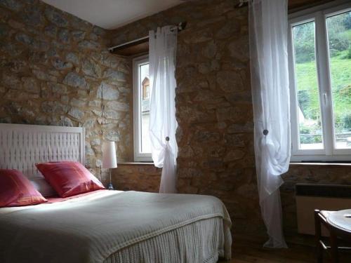 une chambre avec un lit et deux fenêtres dans l'établissement Maison de village en montagne, à Saint-Lary