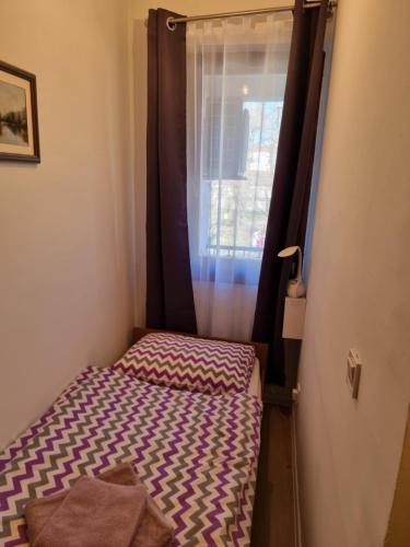 a small bed in a room with a window at Studio apartman Šapudl in Vukovar