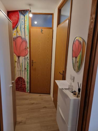a bathroom with a toilet and a door with flowers on the wall at Studio apartman Šapudl in Vukovar