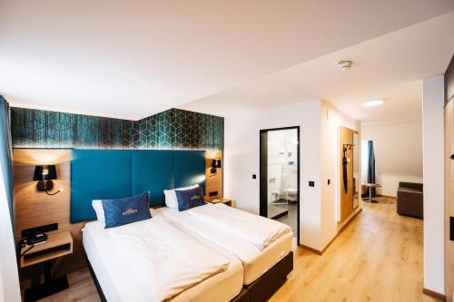 a bedroom with a large bed and a blue wall at Hotel Messmer in Bregenz