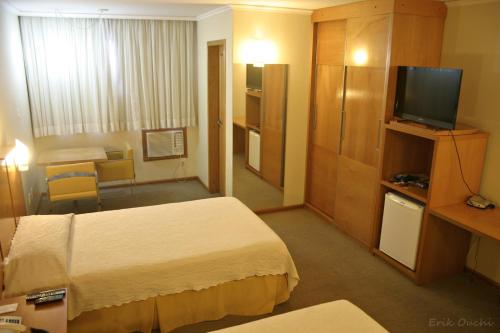 a hotel room with two beds and a television at Barbur Plaza Hotel in Ponta Grossa