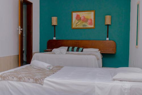 two beds in a room with a green wall at Guarapousada in Guarapari