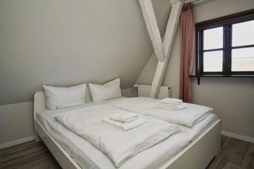 a white bed with two towels on top of it at nah am Meer, ruhige Lage, gratis Nutzung vom AHOI Erlebnisbad und Sauna in Sellin - Haus Büdnerstube FeWo 5 in Middelhagen