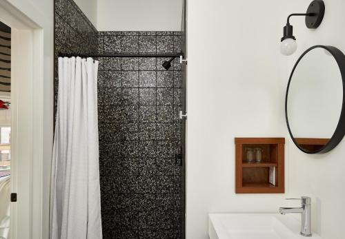 a bathroom with a shower with a sink and a mirror at Field Guide Lodge in Stowe