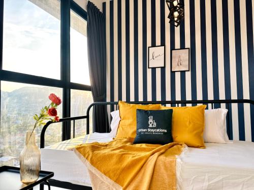 a bedroom with a bed with yellow pillows and a striped wall at New 2BR or 3BR Homey Getaway stay 7 to 10 pax at Urban Suites, Georgetown by URBAN STAYCATION LOD in Jelutong