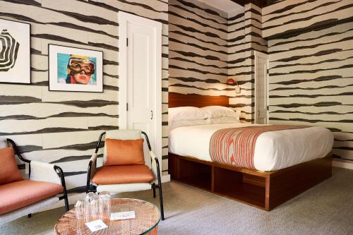 a bedroom with a bed and two chairs and a table at Field Guide Lodge in Stowe