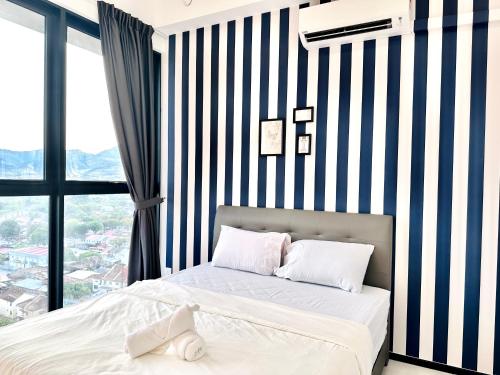 a bedroom with a bed with a striped wall at New 2BR or 3BR Homey Getaway stay 7 to 10 pax at Urban Suites, Georgetown by URBAN STAYCATION LOD in Jelutong