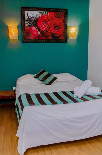 two beds in a room with a painting of roses at Guarapousada in Guarapari
