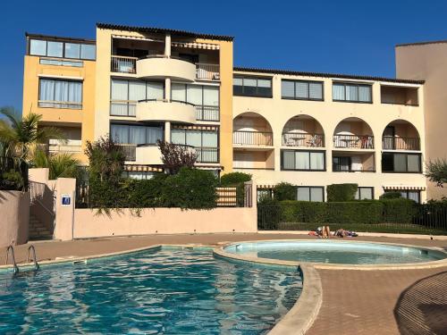 a swimming pool in front of a apartment building at T2 rez de jardin plage piscines vue mer parking terrasse commerces in Six-Fours-les-Plages