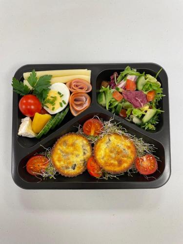 zwei schwarze Tabletts mit Essen, Gemüse und Käse in der Unterkunft Aparthotel Zakopiański & SPA in Zakopane