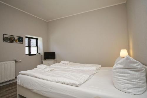 a white bed in a room with a lamp at nah am Meer, ruhige Lage, gratis Nutzung vom AHOI Erlebnisbad und Sauna in Sellin - Haus Büdnerstube FeWo 2 in Middelhagen