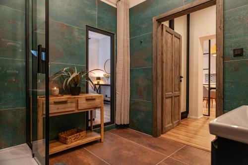 a bathroom with green tiled walls and a wooden table at STING Boutique Apartments in Ostrava