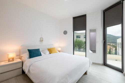 a white bedroom with a large bed and large windows at Korcula Luxury Apartments in Korčula