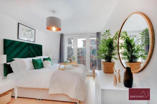 a bedroom with a bed with a mirror and plants at Kingston-upon-Thames - 2 Bed Flat in Kingston upon Thames