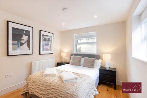 a bedroom with a bed and two lamps and a window at Weybridge - Refurbished Two Bedroom House in Weybridge