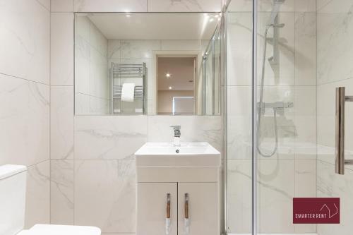 a white bathroom with a sink and a shower at Weybridge - Refurbished Two Bedroom House in Weybridge