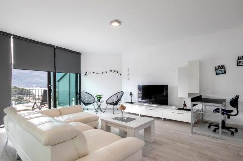 a white living room with a white couch and a piano at Korcula Luxury Apartments in Korčula
