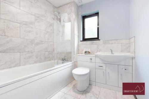 La salle de bains blanche est pourvue d'un lavabo, d'une baignoire et de toilettes. dans l'établissement Isleworth - 4 Bed Modern House, à Brentford
