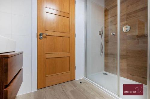 a bathroom with a shower and a wooden door at Sunbury-on-Thames - 4 Bed House in Sunbury Common