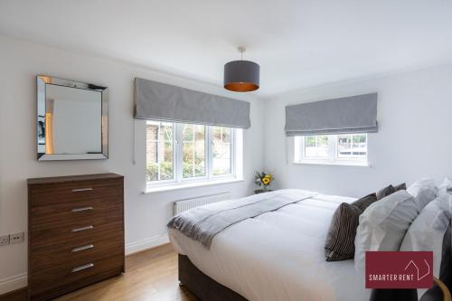 um quarto com uma cama, uma cómoda e 2 janelas em Englefield Green - Modern 2 bedroom Apartment em Englefield Green