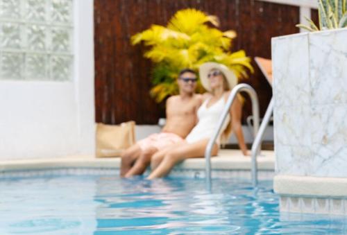 a man and woman sitting next to a swimming pool at Oasis Hotel Waikiki in Honolulu