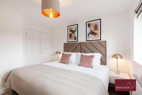 a bedroom with a large white bed with pink pillows at Woking - 2 Bed Eco-Friendly Home in Horsell