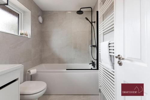 a white bathroom with a tub and a toilet at Woking - 2 Bed Eco-Friendly Home in Horsell
