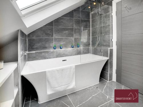 a bathroom with a white tub and a sink at Shepperton - 3 Bedroom Home in Walton-on-Thames
