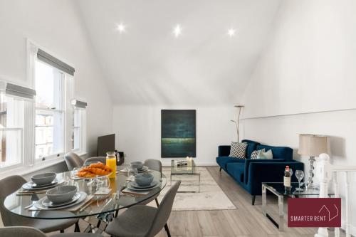 sala de estar con mesa y sofá azul en Richmond - 2 Bedroom Duplex Apartment, en Richmond upon Thames