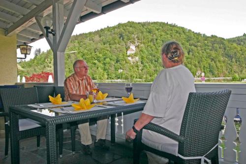 two men sitting at a table on a patio at Ferienwohnungen beim Hotel zur Post, Erlau in Erlau