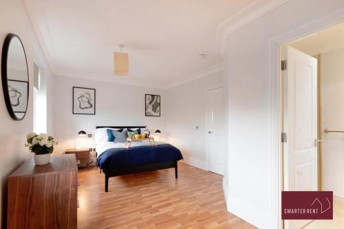 a bedroom with a blue bed and a wooden floor at Richmond - 5 Bedroom Townhouse with Parking & Garden in London