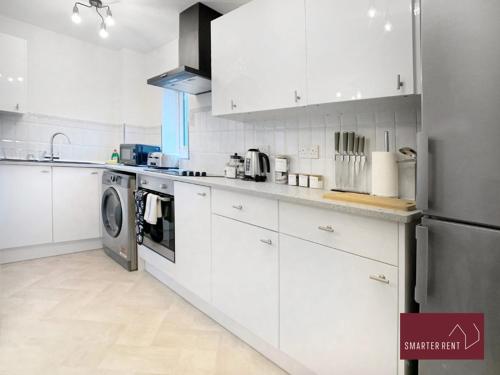eine Küche mit weißen Schränken, einer Waschmaschine und einem Trockner in der Unterkunft Bracknell - 1 Bedroom House - With Parking in Bracknell
