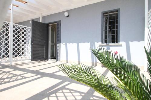 a white house with a black door and a plant at Anagnina Apartment in La Romanina