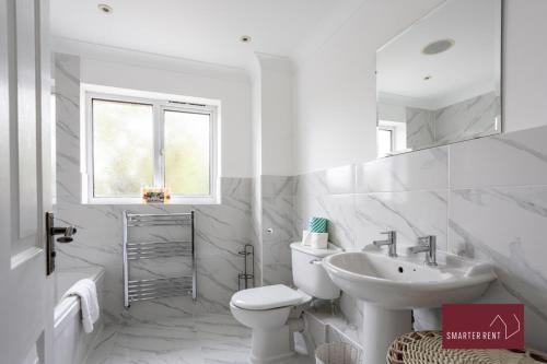 La salle de bains blanche est pourvue de toilettes et d'un lavabo. dans l'établissement Wimbledon - 4 Bedroom Home With Parking, Garden & Office, à Londres