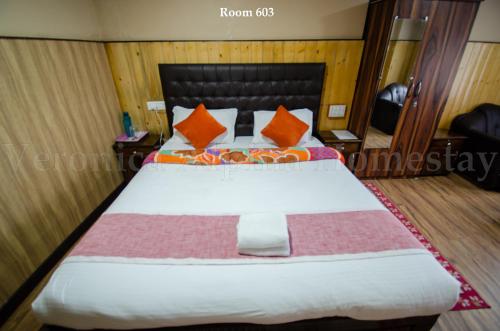 a hotel room with a bed with orange pillows at Veronica Alpina Mountain View Home in Darjeeling