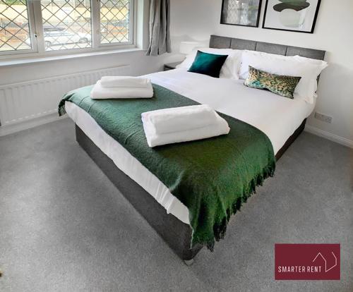 a bedroom with a large bed with two pillows on it at Knaphill, Woking - 2 Bedroom House - Garden and Parking in Brookwood