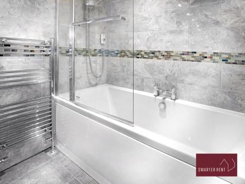 Wokingham - 2 Bedroom Maisonette - With Parking في وكينغهام: حوض استحمام أبيض في حمام مع دش