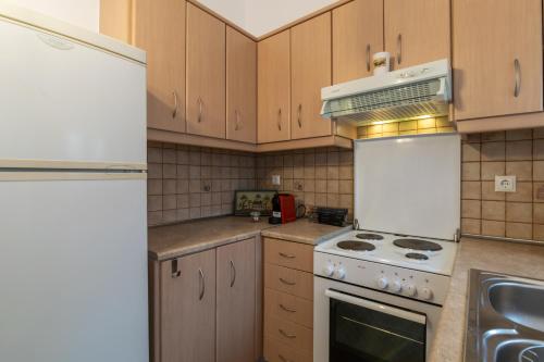 cocina con armarios de madera y horno de fogón blanco en Malum Sunset View, en Tripití