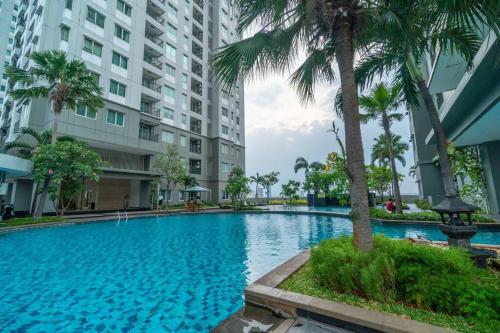 a large swimming pool with palm trees and buildings at Comfy 1-bedroom city view @ central Jakarta, SCBD in Jakarta