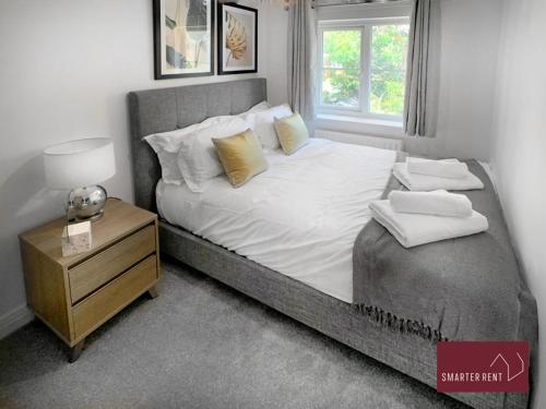 Wokingham - 2 Bedroom House - With Garden في وينرش: غرفة نوم مع سرير كبير مع منضدة ونافذة