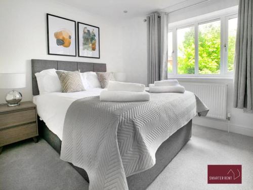 a bedroom with a large bed with white blankets and pillows at Twyford - Modern 2 Bedroom House - Garden and Parking in Twyford