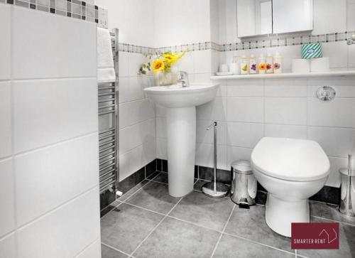 a white bathroom with a toilet and a sink at Twyford - Modern 2 Bedroom House - Garden and Parking in Twyford